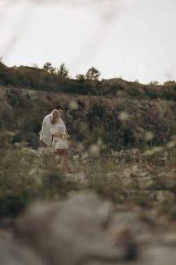 Hamile anne ve tatlı baba doğada gün batımında yürüyorlar. 