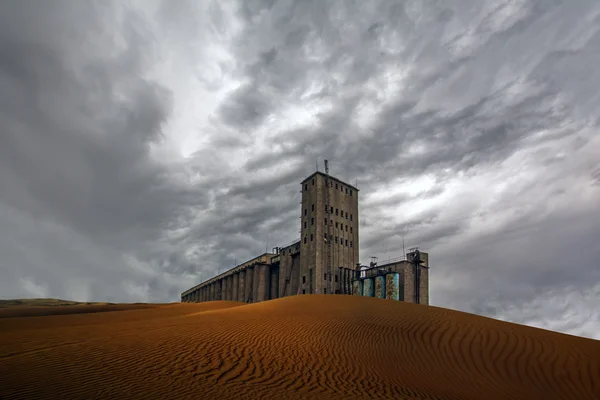 Postapocalyptic view of grain elevator in desert under cloudy sky — Stock Photo, Image