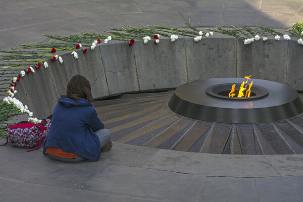 a girl mourns at Eternal flame at the Tsitsernakaberd memorial monument of the Armenian Genocide, Yerevan, Armenia. On 24th of April, 1915, 1.5 million civilian Armenians were killed by Ottoman Empire