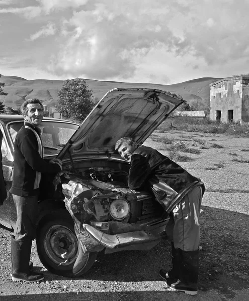 Sevan, Armenia - 08 de julio de 2012: Hombres examinando el viejo automóvil estrellado con capucha abierta — Foto de Stock