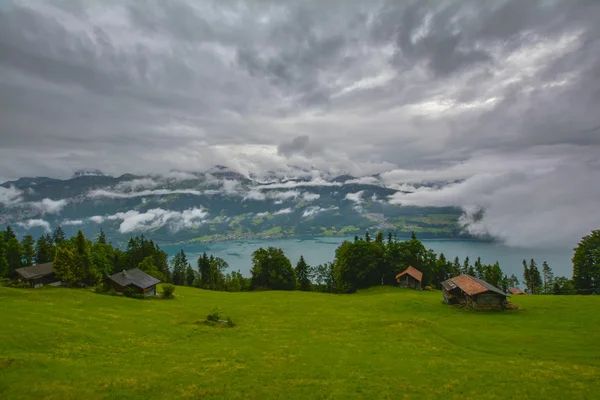 Blick auf Hütten und Thunersee am Hang der bewaldeten Berge in den Schweizer Alpen an einem bewölkten Tag. beatenberg, schweiz — Stockfoto