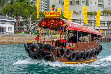 Hong Kong, Çin - 22 Şubat 2014: Shum Wan Rıhtımı 'nın turkuaz sularında yüzen kırmızı çatılı turist feribotu siyah kullanılmış araba lastikleri ve sarı bayraklar