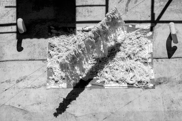 Washed white sheep wool for making beds and quilts are dried on sunny day. Black and white photography with contrast shadows, aerial view