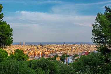 Barselona, İspanya 'nın renkli panoramik manzarası tepeden yeşil ağaçlara doğru mavi deniz ve gökyüzü. Şehir gün batımında aydınlandı.