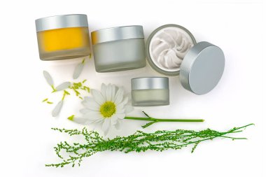 Yüz için nemlendirici krem içeren açık gümüş kapaklı cam kozmetik kavanozlar ve kırpma yolu olan beyaz arka planda izole edilmiş papatya çiçeği. Üst görünüm, düz konum.