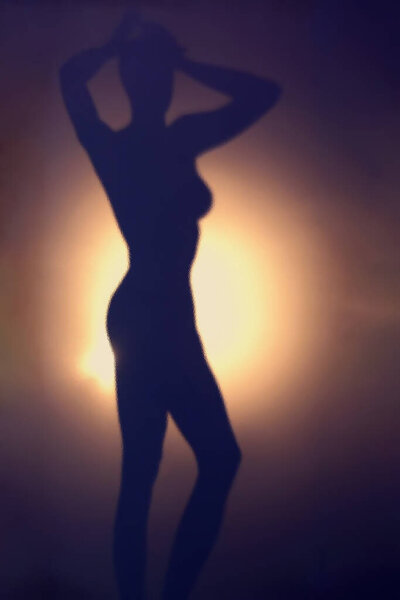 Abstract dynamic scene with sexy woman dancing in front of backlight on gradient blue and orange background. Silhouette is seen through the dimpled glass