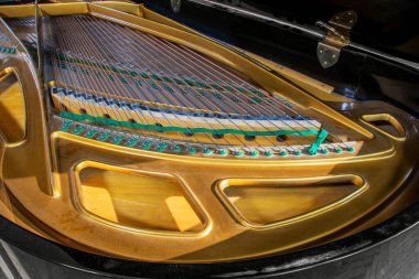 Siyah piyanonun içindeki tellere ve iğnelere yakından bak. Kapağın altındaki altın piyano çerçevesi. Klasik müzik aletleri koleksiyonu