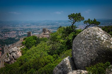 Portekiz, Sintra 'daki antik Moors Kalesi ve Pena Sarayı ile panoramik manzara yeşil orman ve tepenin üzerinde büyük kayalarla çevrili.