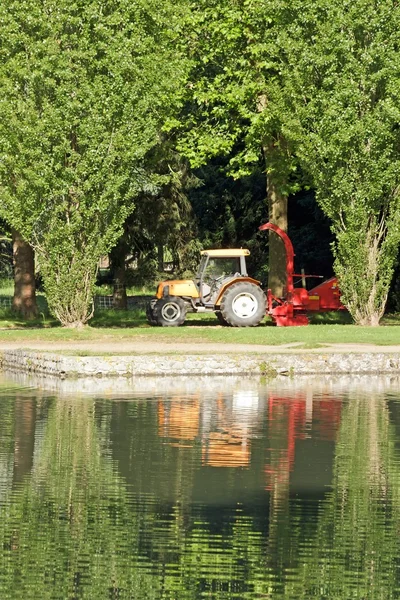 Traktor a huňaté pod stromy, zemědělské stroje, které čekají na použití — Stock fotografie