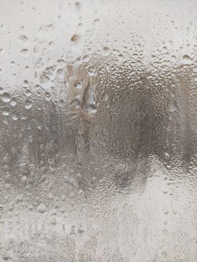 Donmuş su damlaları cama düşer.