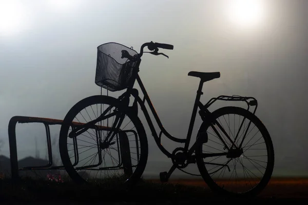 雾蒙蒙的夜晚 骑自行车站在背光下的轮廓 — 图库照片