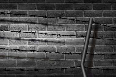 Aydınlatılmış tuğla duvara dikenli tellerin gölgesi.