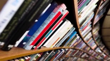 Kütüphanedeki kitaplarla kıvrımlı raflarda hareket eden kamera