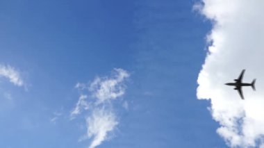 Mavi gökyüzünde beyaz bulutlu uçağın alçak açılı görüntüsü