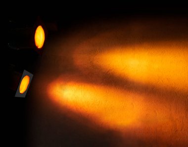 turuncu ya da sarı projektörler dokulu duvarda desen oluşturuyor