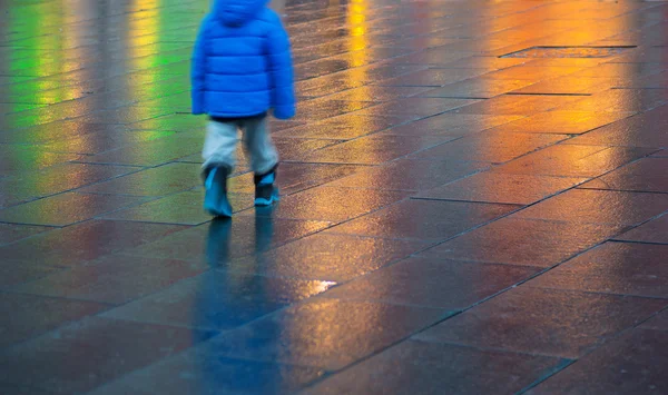 Young boy walking on wet pavement — Stock Photo, Image