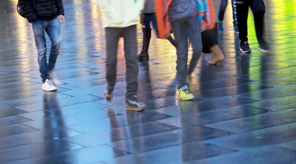 Menschen gehen auf nassem Bürgersteig — Stockfoto