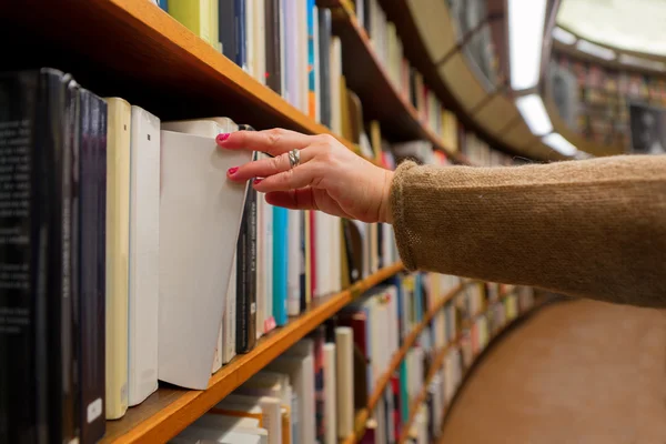 Frau wählt ein Buch aus — Stockfoto