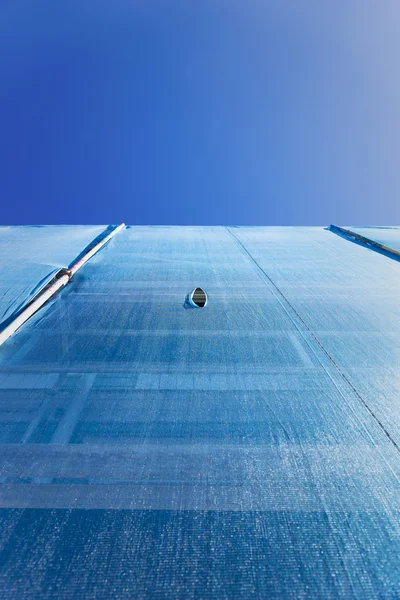 Gebäude mit Gerüsten, drapiert in blauem Schuttnetz lizenzfreie Stockfotos
