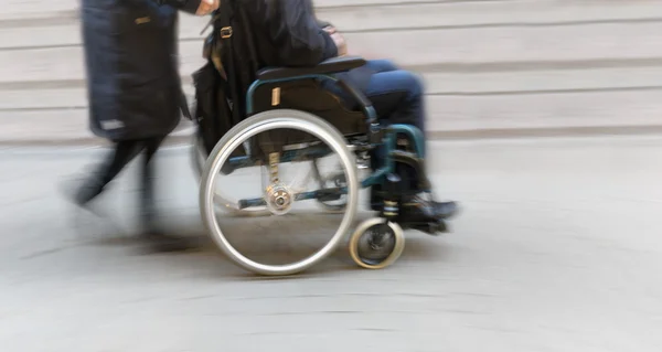 Homme en fauteuil roulant poussé par la femme — Photo