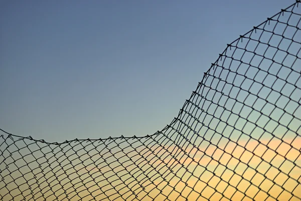 Zincir bağlantı çit akşam gökyüzü üzerinde — Stok fotoğraf