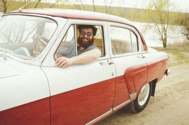 Retro bir arabanın direksiyonuna sakallı adam