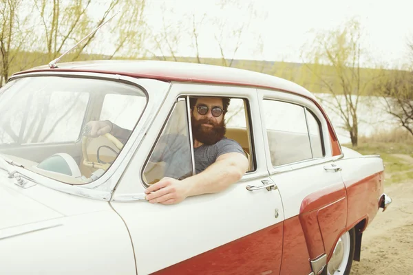 Bearded man behind the wheel of a retro car