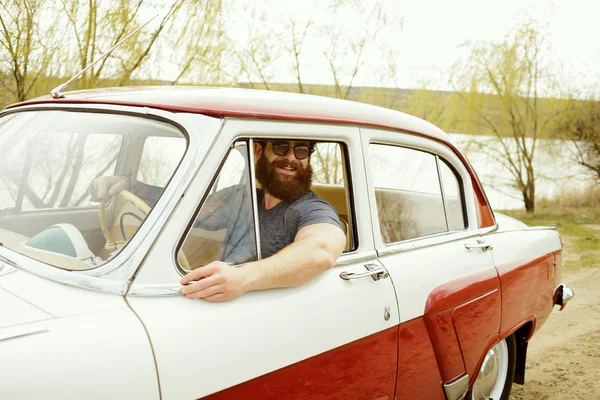 Bearded man behind the wheel of a retro car