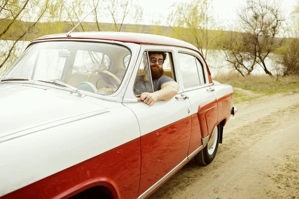 Bearded man behind the wheel of a retro car