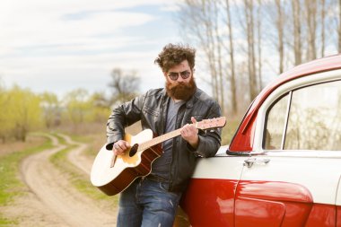 Sakallı adam açık havada retro car yakınındaki gitar çalmak