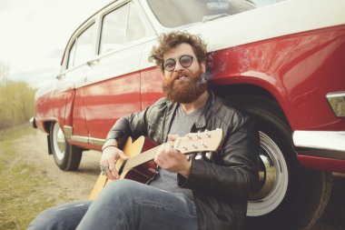 Sakallı adam açık havada retro car yakınındaki gitar çalmak