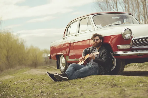 Bärtiger Mann spielt Gitarre im Freien in der Nähe von Retro-Auto — Stockfoto