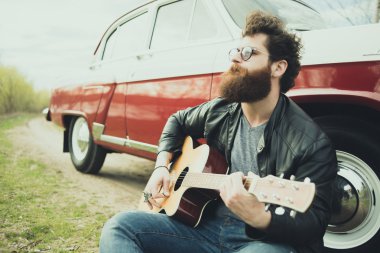 Sakallı adam açık havada retro car yakınındaki gitar çalmak
