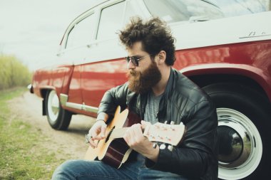 Sakallı adam açık havada retro car yakınındaki gitar çalmak