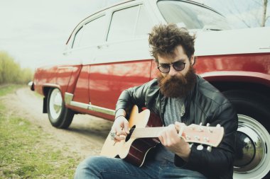 Sakallı adam açık havada retro car yakınındaki gitar çalmak