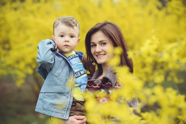 Matka a syn šťastná v parku poblíž žluté květy — Stock fotografie