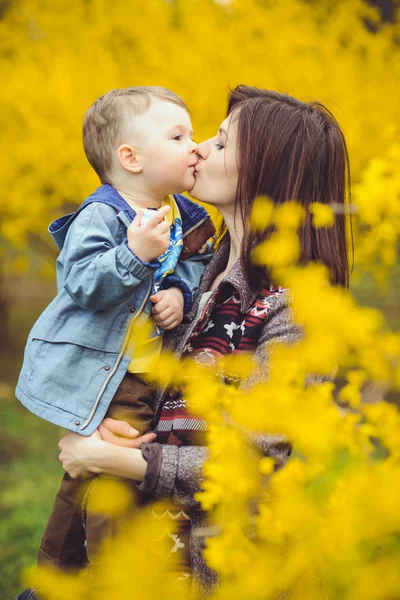 Mère et fils heureux dans le parc, près des fleurs jaunes — Photo