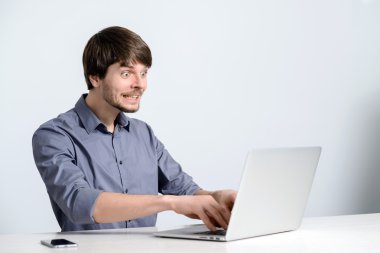 Dizüstü bilgisayarda çalışan genç adam.