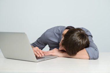 Dizüstü bilgisayarda çalışan genç adam.