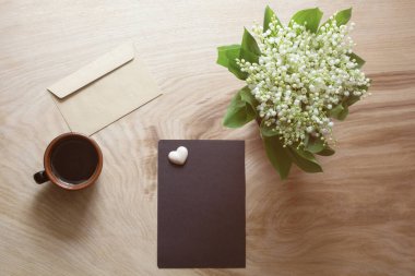Koyu bir kağıt, bahar çiçekleri, tahtadan bir fincan kahve.