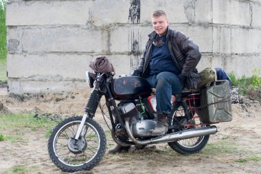 Mahvolmuş binanın yakınında motosikletli kıyamet sonrası bir adam.