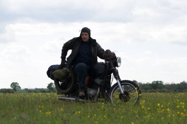 Meadow 'da motosiklet süren kıyamet sonrası bir adam.