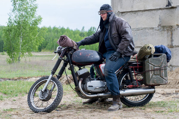 A post apocalyptic man on motorcycle near destroyed building