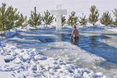 Bir adam Hristiyan bayramında haç şeklinde bir deliğe dalıyor.