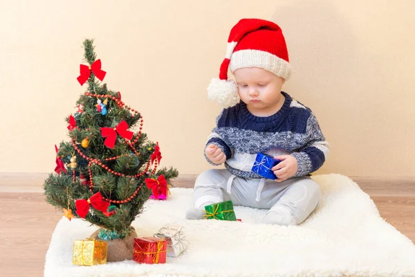 Смешной Ребенок Шляпе Санта Клауса Сидит Рядом Елкой Маленькими Подарками — стоковое фото