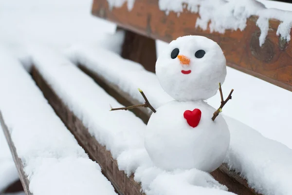 Χαρούμενος Χιονάνθρωπος Κόκκινη Καρδιά Ένα Χιονισμένο Παγκάκι — Φωτογραφία Αρχείου