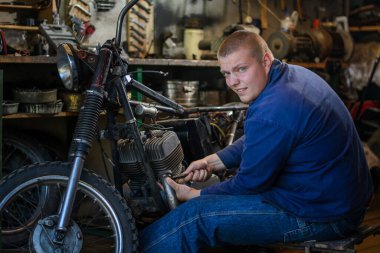 Atölyede motosiklet tamir eden bir adam.