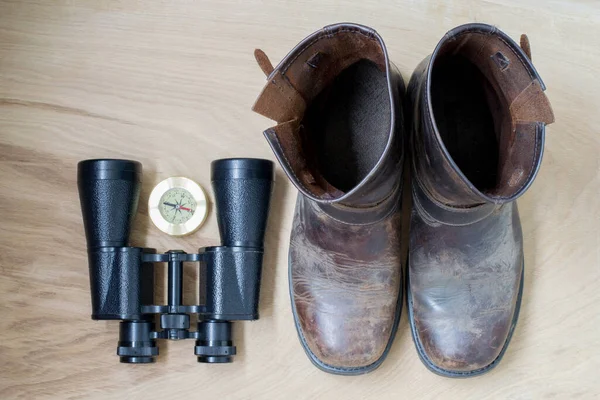 Binoculars, boots and compass, traveler\'s things, on the wooden background