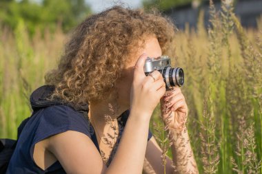 Klasik kameralı kız çimlerin üzerinde duruyor.