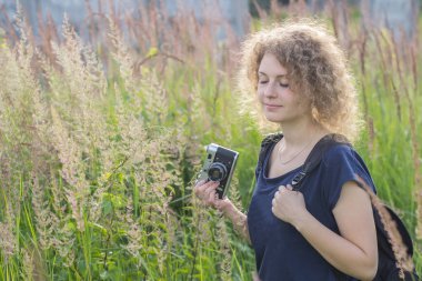Klasik kameralı kız çimlerin üzerinde duruyor.